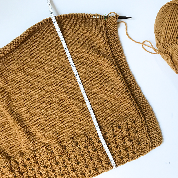 photo of the back of the Happy Harvest poncho with a tape measure to show the length